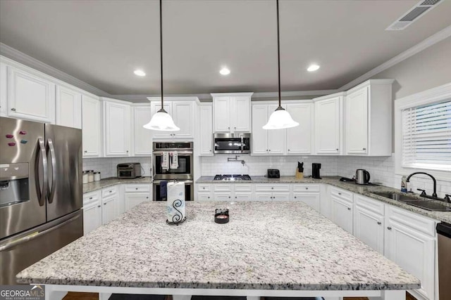 kitchen with decorative backsplash, appliances with stainless steel finishes, a kitchen island, a sink, and visible vents