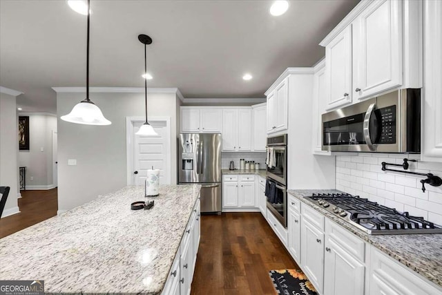 kitchen featuring decorative backsplash, appliances with stainless steel finishes, white cabinets, a center island, and crown molding