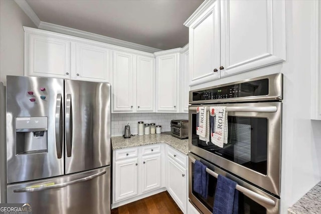 kitchen featuring light stone countertops, decorative backsplash, stainless steel appliances, white cabinets, and dark wood-style floors