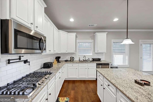 kitchen featuring white cabinets, stainless steel appliances, crown molding, and a sink
