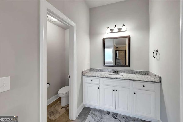 full bath with toilet, a shower, vanity, and baseboards