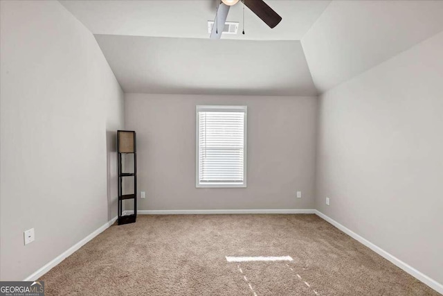 carpeted spare room featuring visible vents, ceiling fan, vaulted ceiling, and baseboards