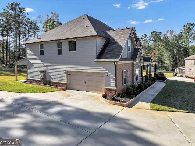 view of home's exterior with roof with shingles, concrete driveway, brick siding, an attached garage, and a lawn