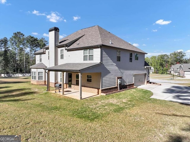 back of house with a patio area, a lawn, driveway, a chimney, and an attached garage
