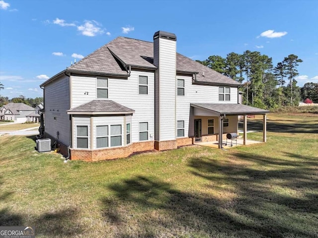 back of house featuring a lawn, a chimney, central air condition unit, and a patio