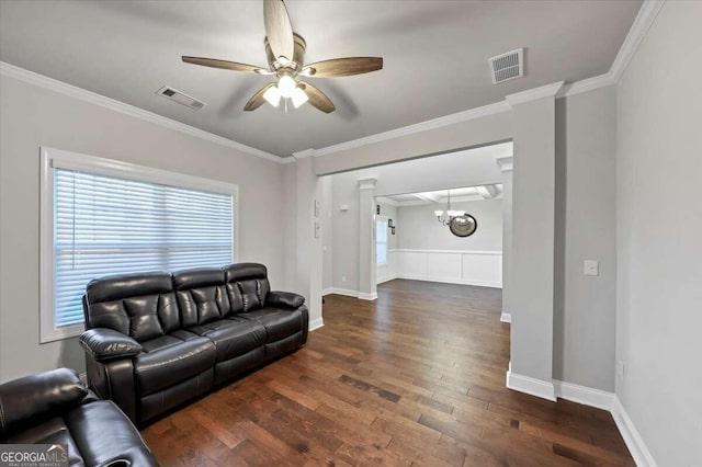 living room featuring wood finished floors, visible vents, ornamental molding, and ceiling fan with notable chandelier