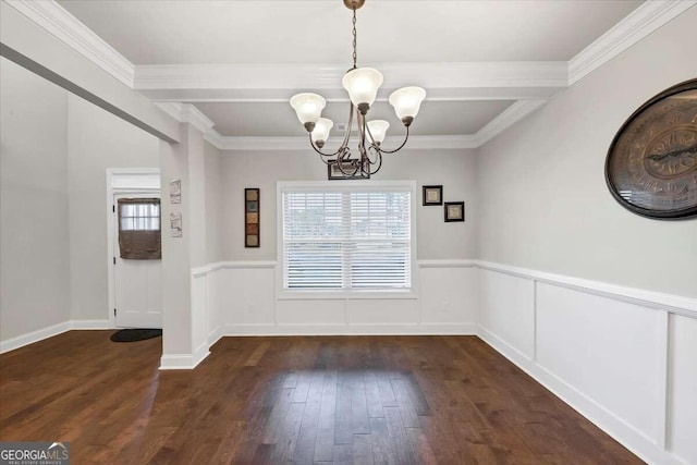 unfurnished dining area featuring dark wood finished floors, a wainscoted wall, an inviting chandelier, and ornamental molding