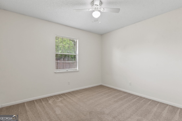 spare room with a ceiling fan, baseboards, carpet, and a textured ceiling