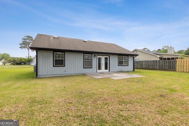 back of property with fence, french doors, a lawn, and a patio