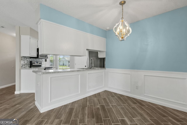 kitchen featuring white cabinetry, a wainscoted wall, an inviting chandelier, electric range, and dark wood-type flooring