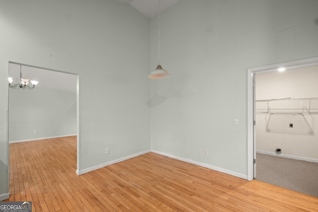 3592 Lakeview Dr, Gainesville, GA 30501 - unfurnished room featuring baseboards, high vaulted ceiling, an inviting chandelier, and light wood-style floors