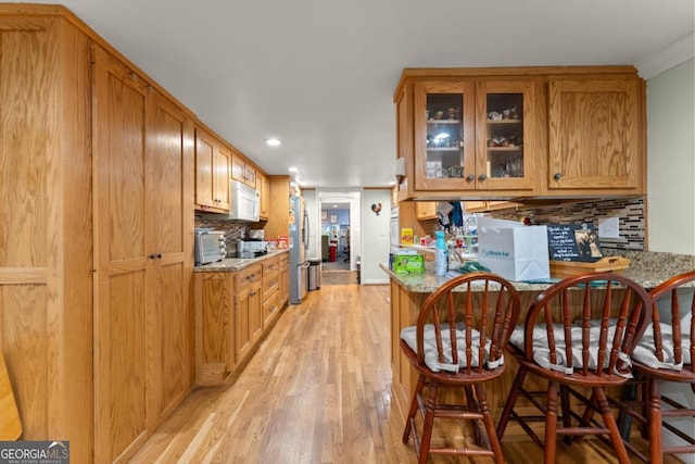 5855 Willis Ln, Cumming, GA 30040 - kitchen featuring glass insert cabinets, white microwave, freestanding refrigerator, backsplash, and light wood finished floors