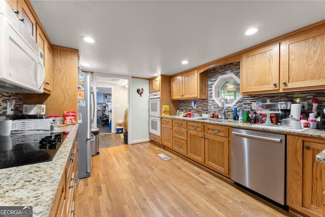 5855 Willis Ln, Cumming, GA 30040 - kitchen featuring decorative backsplash, a sink, appliances with stainless steel finishes, light wood-style floors, and visible vents
