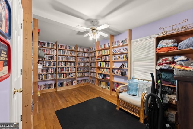 5855 Willis Ln, Cumming, GA 30040 - living area with wall of books, a ceiling fan, and wood finished floors