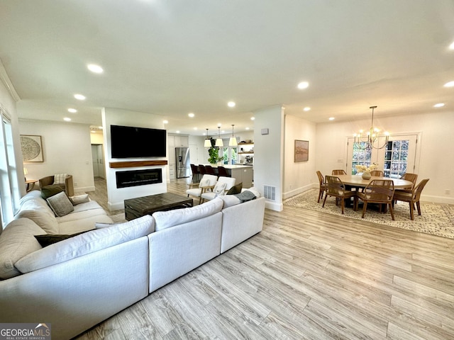 3550 N Bogan Rd, Buford, GA 30519 - living area with baseboards, recessed lighting, light wood-style flooring, a chandelier, and a glass covered fireplace