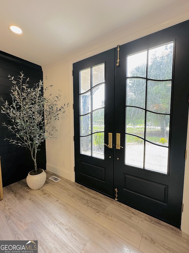 doorway to outside featuring crown molding, a wealth of natural light, french doors, and light wood-type flooring