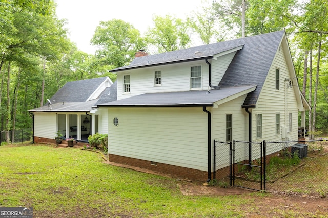 back of property featuring fence, a chimney, a gate, central AC unit, and a lawn