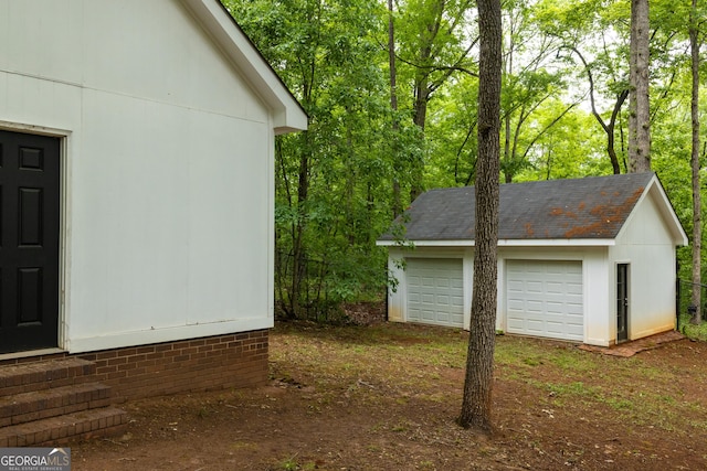 view of property exterior with a detached garage, an outdoor structure, and entry steps