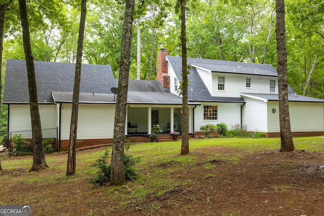 rear view of house with a porch, crawl space, a chimney, fence, and a shingled roof