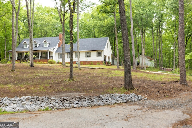 cape cod home featuring a porch and a chimney