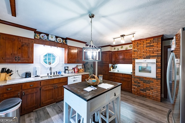kitchen with a sink, decorative backsplash, white appliances, and light wood-style flooring