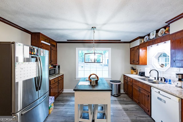 kitchen with a sink, ornamental molding, stainless steel appliances, and dark wood-style floors