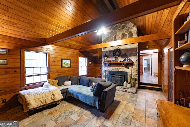living room with wood walls, a fireplace, beamed ceiling, stone finish floor, and wooden ceiling