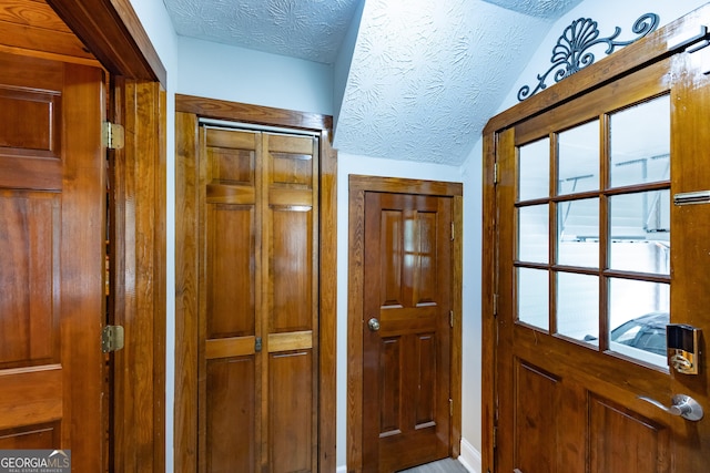 doorway to outside with a textured ceiling and vaulted ceiling