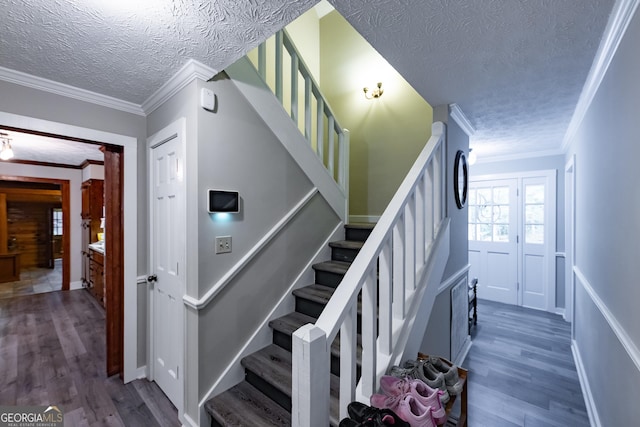staircase featuring a textured ceiling, ornamental molding, and wood finished floors
