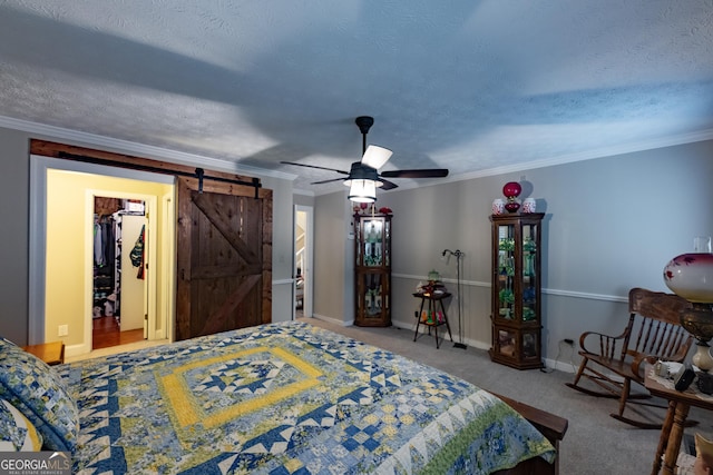 bedroom with a walk in closet, ornamental molding, baseboards, and a barn door