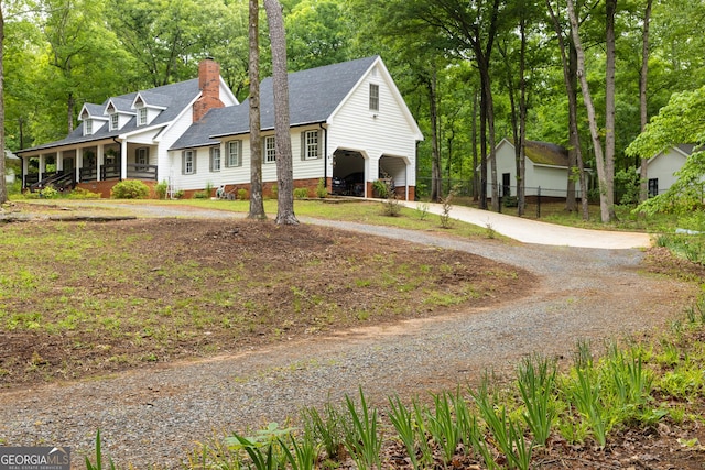 cape cod house featuring covered porch, driveway, a chimney, roof with shingles, and fence