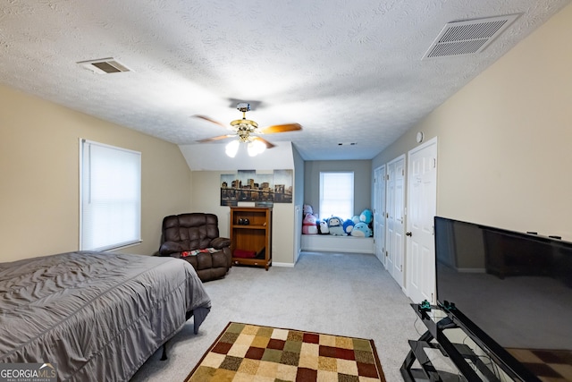 bedroom featuring visible vents, a textured ceiling, ceiling fan, and light carpet