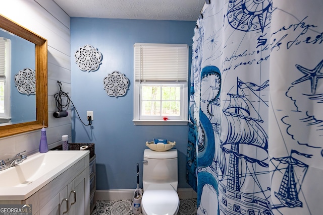 bathroom featuring curtained shower, baseboards, tile patterned floors, vanity, and toilet