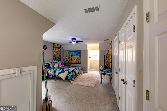 carpeted bedroom featuring a ceiling fan, a textured ceiling, and visible vents
