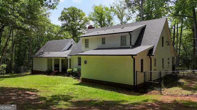 rear view of house with a lawn, fence, a chimney, and a gate