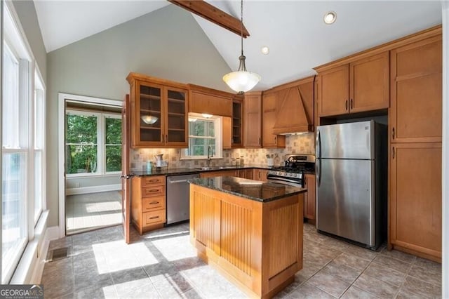 kitchen with brown cabinetry, a healthy amount of sunlight, high vaulted ceiling, and stainless steel appliances