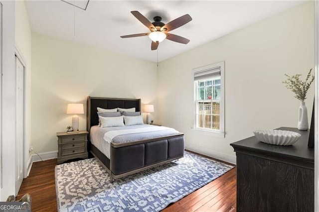 bedroom featuring baseboards, ceiling fan, attic access, and dark wood finished floors