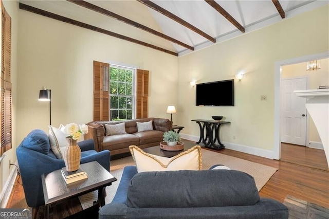living area featuring baseboards, vaulted ceiling with beams, and wood finished floors