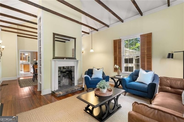 living area featuring a fireplace with raised hearth, baseboards, vaulted ceiling with beams, and hardwood / wood-style flooring