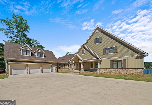 craftsman house featuring driveway, board and batten siding, a porch, and stone siding