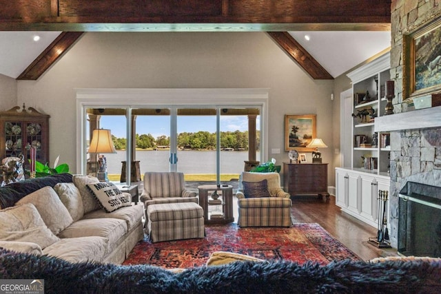 living room with vaulted ceiling with beams, wood finished floors, a water view, a stone fireplace, and french doors