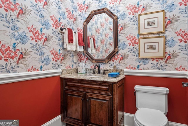 bathroom with wallpapered walls, toilet, and vanity