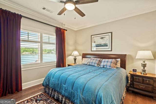 bedroom with ceiling fan, crown molding, visible vents, baseboards, and wood finished floors