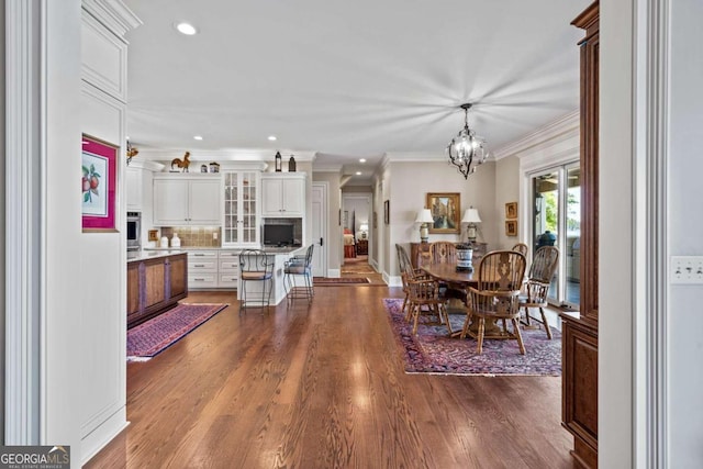 dining area with a chandelier, recessed lighting, crown molding, and dark wood-style floors