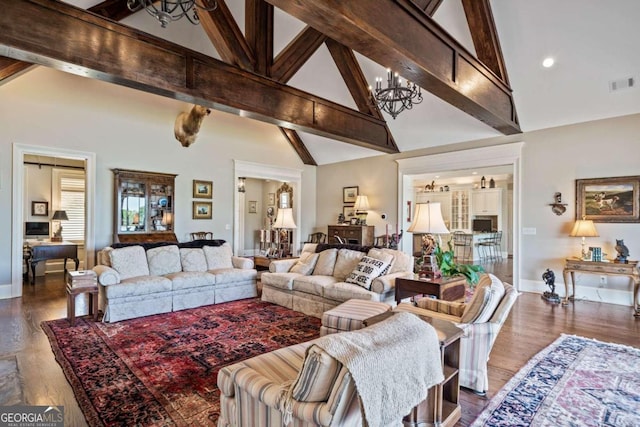living room with wood finished floors, beamed ceiling, visible vents, a notable chandelier, and high vaulted ceiling