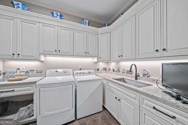 washroom with dark wood-style floors, a sink, cabinet space, washer and clothes dryer, and ornamental molding