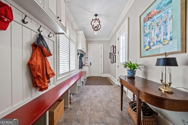mudroom with stone finish floor, a healthy amount of sunlight, crown molding, and baseboards