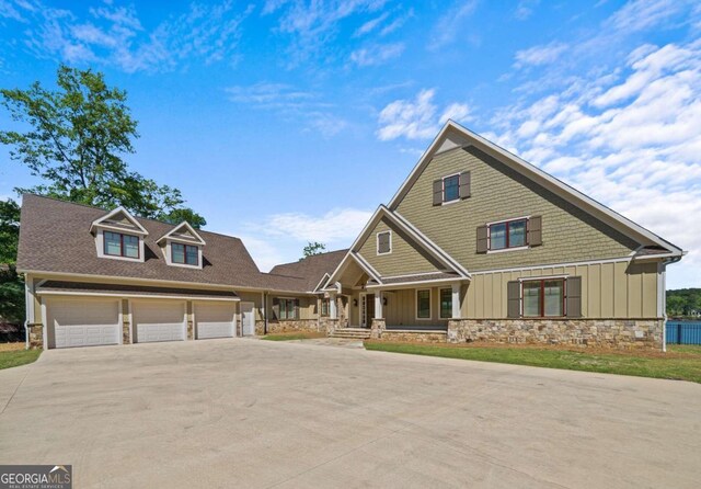 craftsman-style home featuring driveway, board and batten siding, a porch, and stone siding