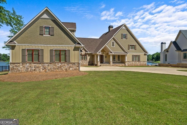 craftsman inspired home featuring board and batten siding, a front lawn, concrete driveway, and stone siding
