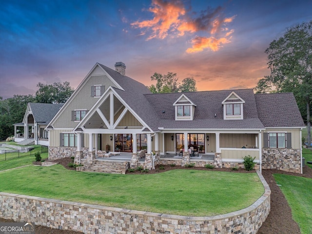 back of property at dusk featuring board and batten siding, covered porch, and a chimney